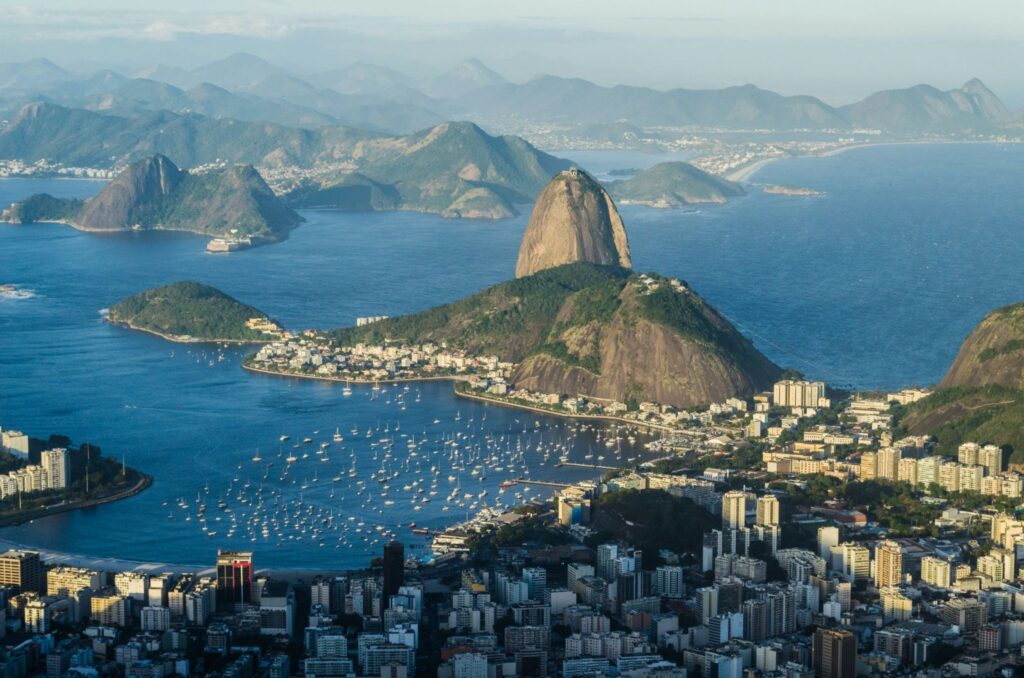 Vista aérea panorâmica da cidade do Rio de Janeiro mostrando o Morro do Pão de Açúcar e barcos ancorados na Baía de Guanabara, ilustrando as opções de destinos nacionais ao escolher o melhor programa de milhas.